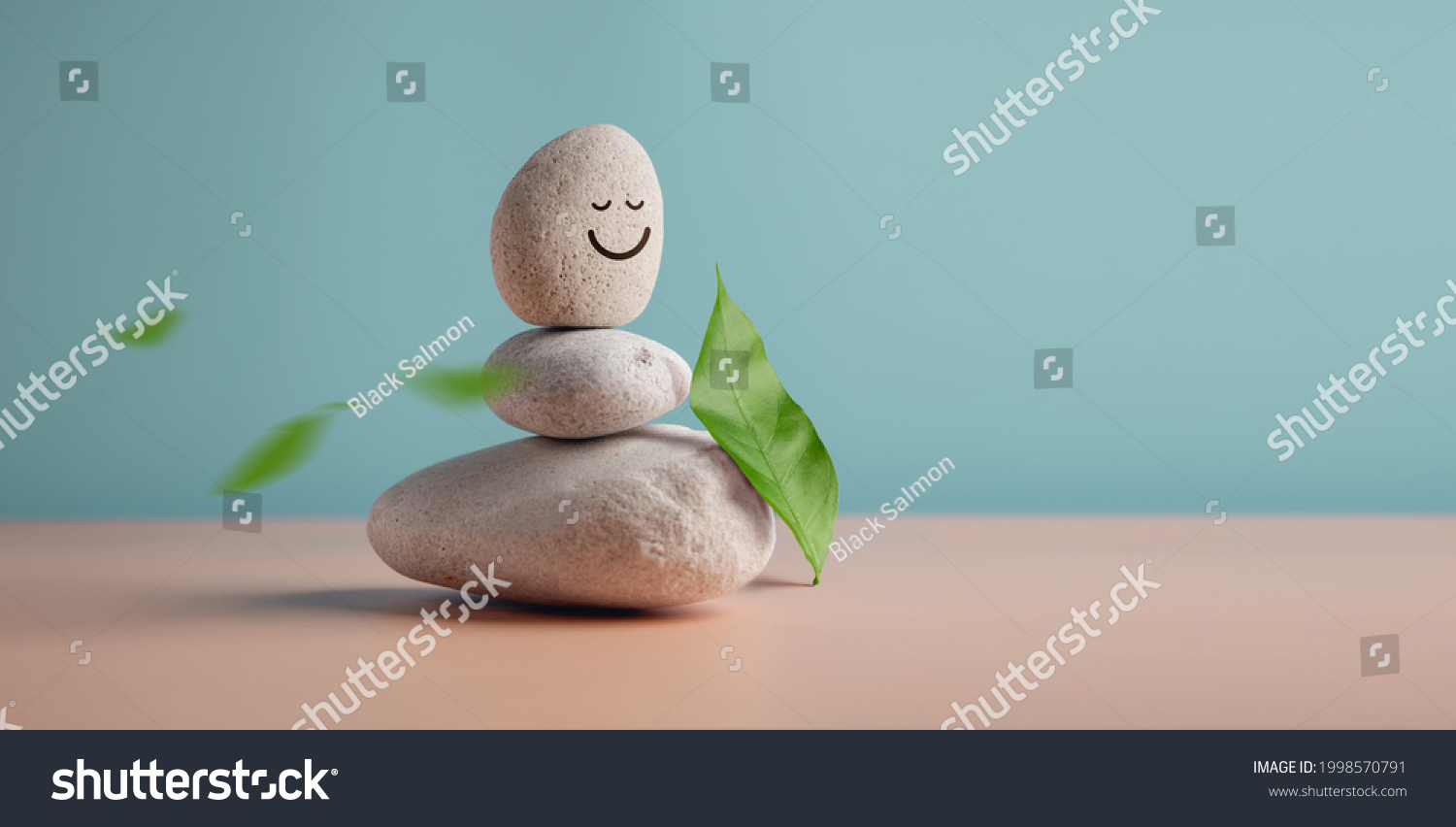 Enjoying Life, Harmony and Positive Mind Concept. Stack of Stable Pebble Stone with Smiling Face Cartoon and Leaf. Serene, Balancing Body, Mind, Soul and Spirit. Mental Health Practice #1998570791