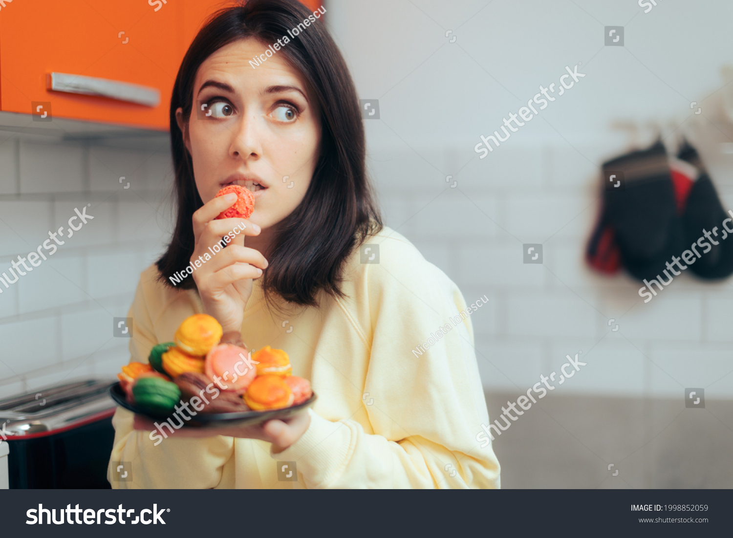 Woman Eating Macarons Feeling Guilty and Hiding. Adult person with sugar addiction hiding her alimentary habits over indulging because of stress
 #1998852059