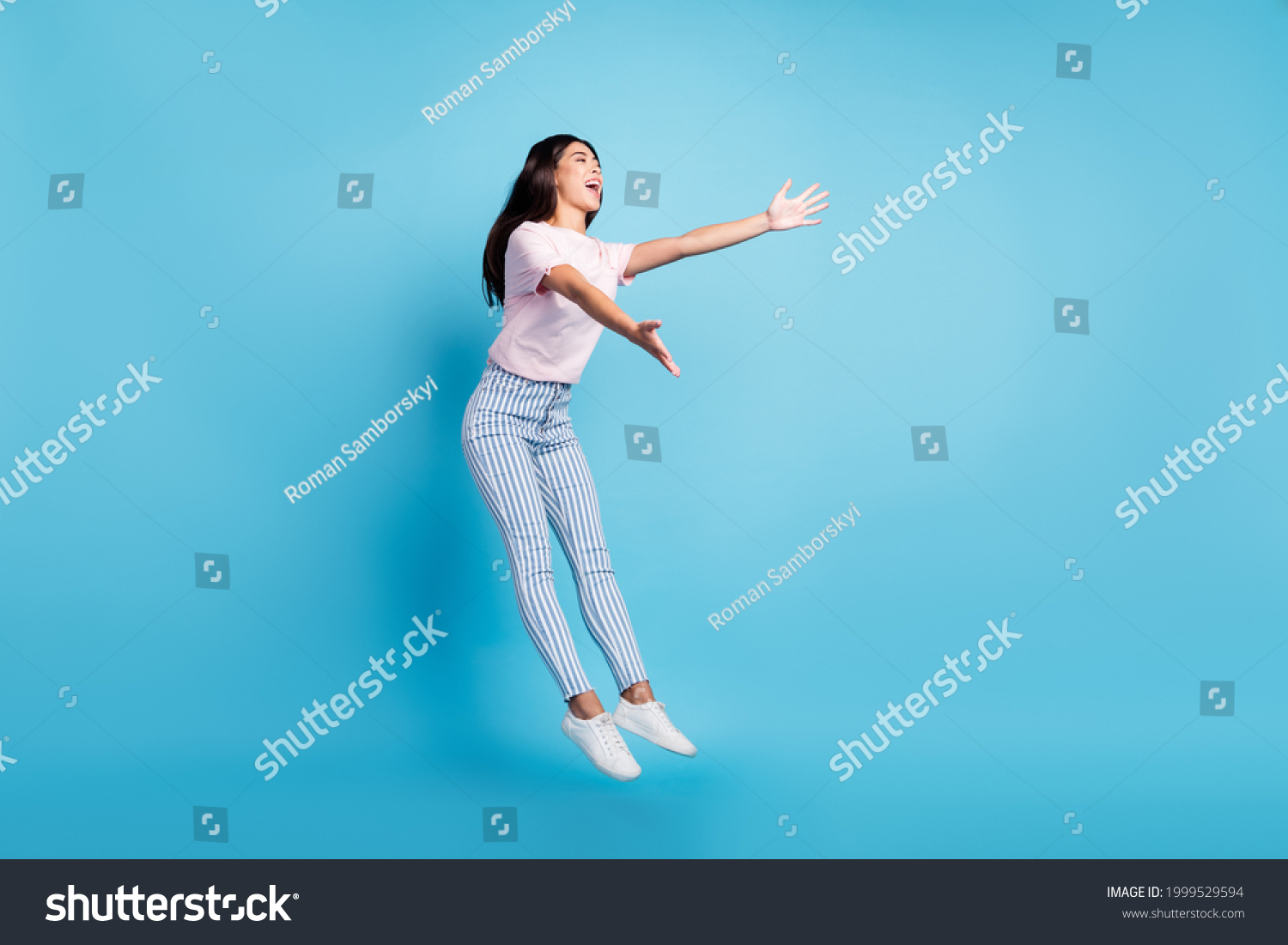 Full size photo of attractive young charming woman open hands empty space jump isolated on blue color background #1999529594