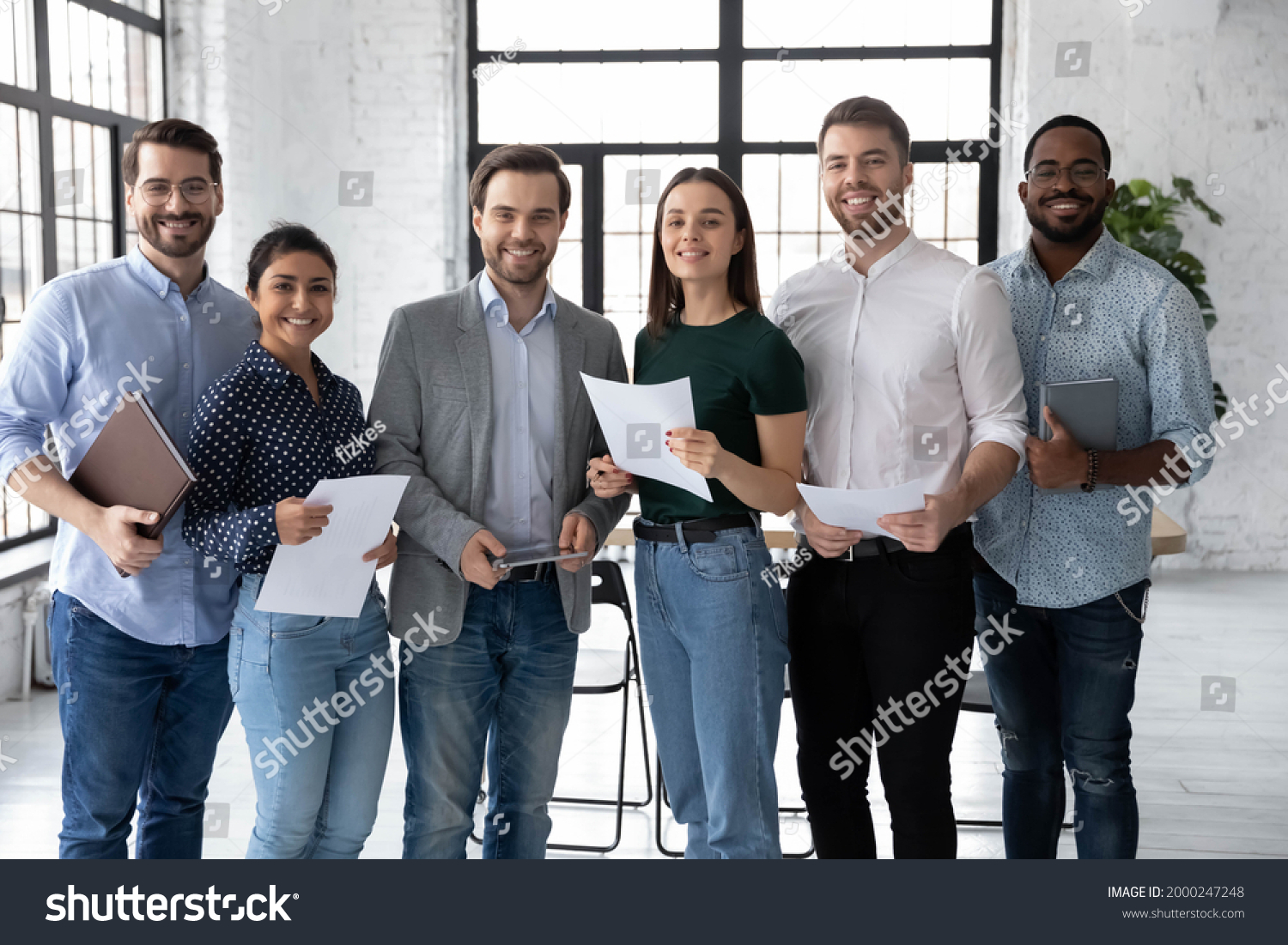 Portrait of happy diverse group of interns or students and corporate teacher after successfully passes exam. Multi ethnic business team of employees holding paper documents, looking at camera, smiling #2000247248