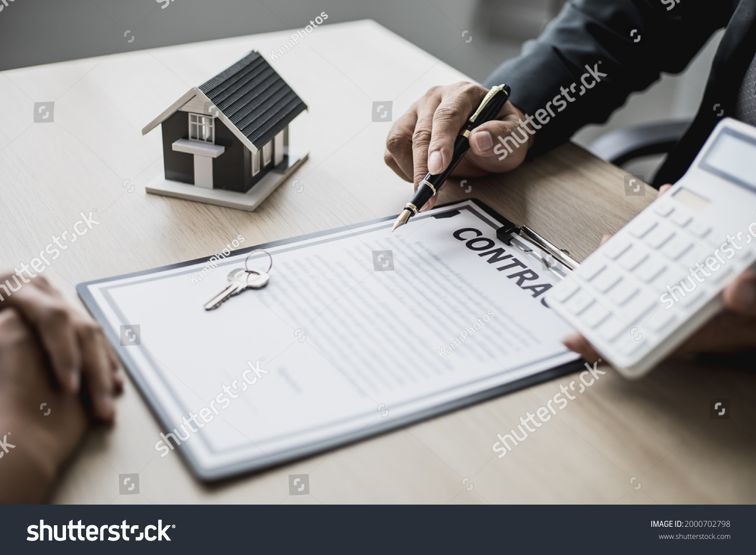 Employees use the calculator to calculate monthly rent for tenants and explain renting details and calculate monthly rent payments to tenants before signing the contract. Renting a house concept. #2000702798