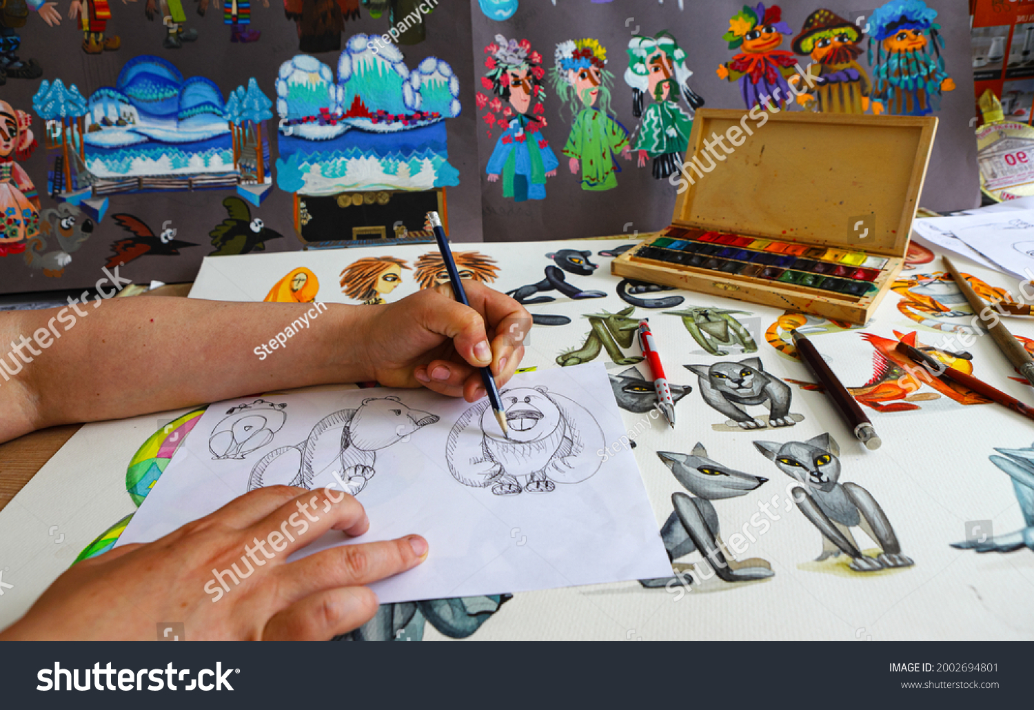 The animator draws with a pencil and draws characters from cartoons, comics or puppet shows. Preparing to make a doll. The designer creates sketches. Comics, cartoons, puppet theater #2002694801
