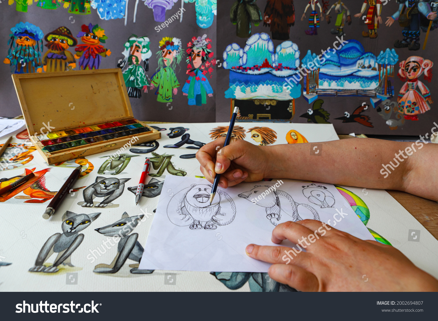 The animator draws with a pencil and draws characters from cartoons, comics or puppet shows. Preparing to make a doll. The designer creates sketches. Comics, cartoons, puppet theater #2002694807