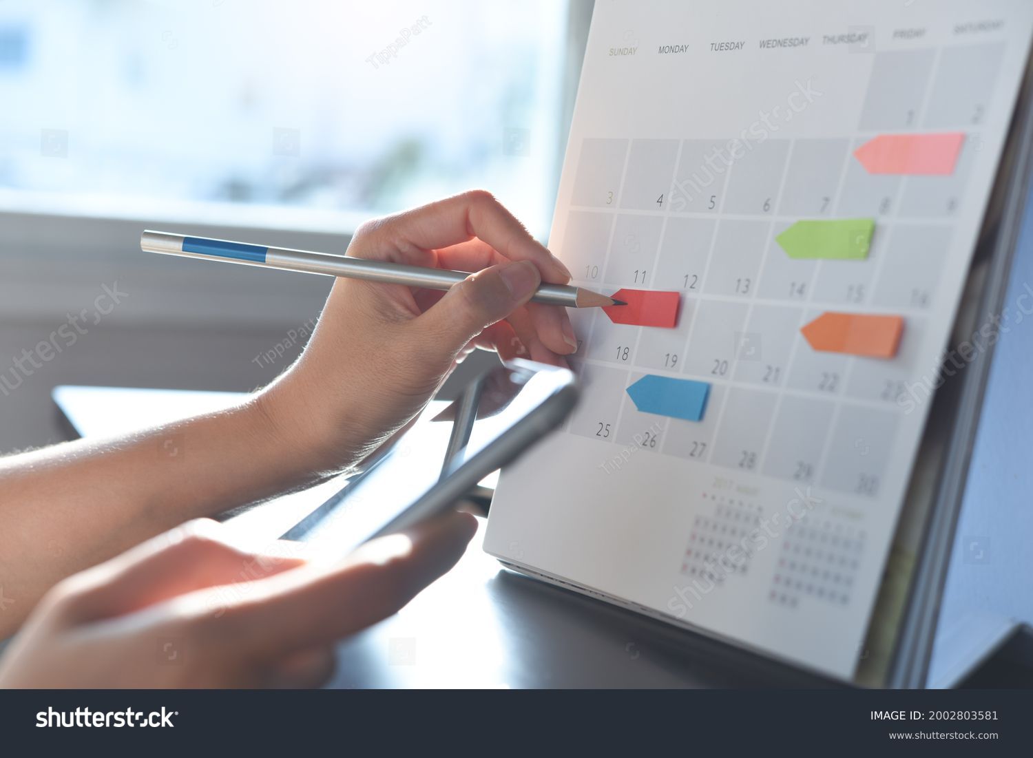 2024 Event planner timetable agenda plan on schedule event. Business woman checking planner on mobile phone, taking note on calendar desk on office table. Calendar event plan, work planning #2002803581