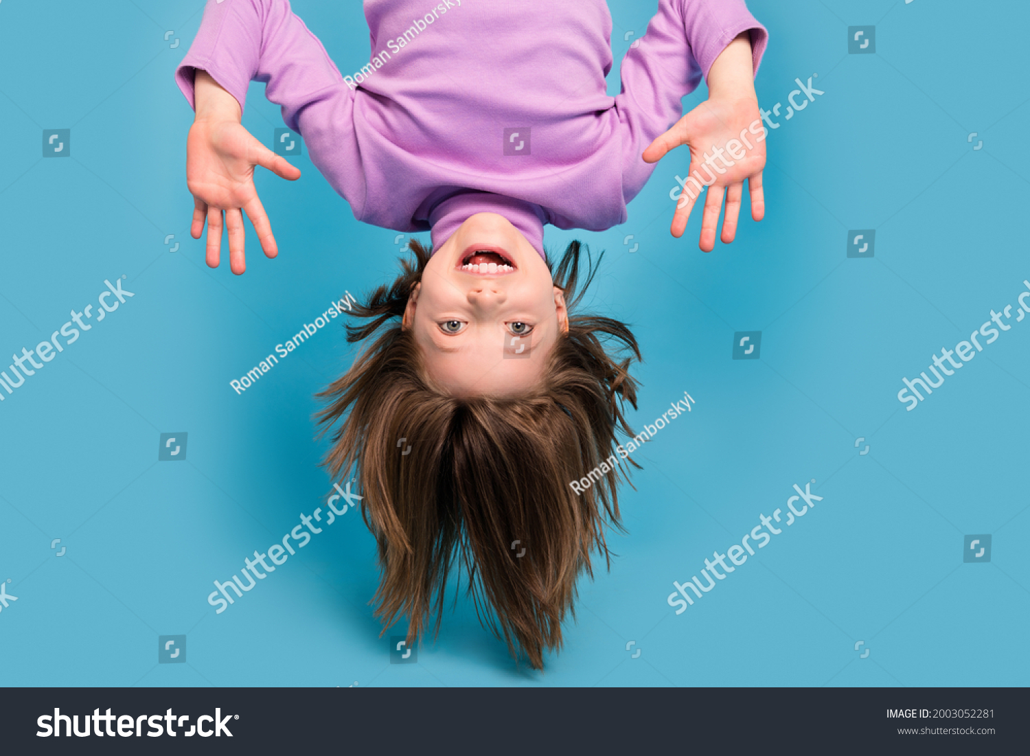 Portrait photo little girl hanging upside down isolated pastel blue color background #2003052281