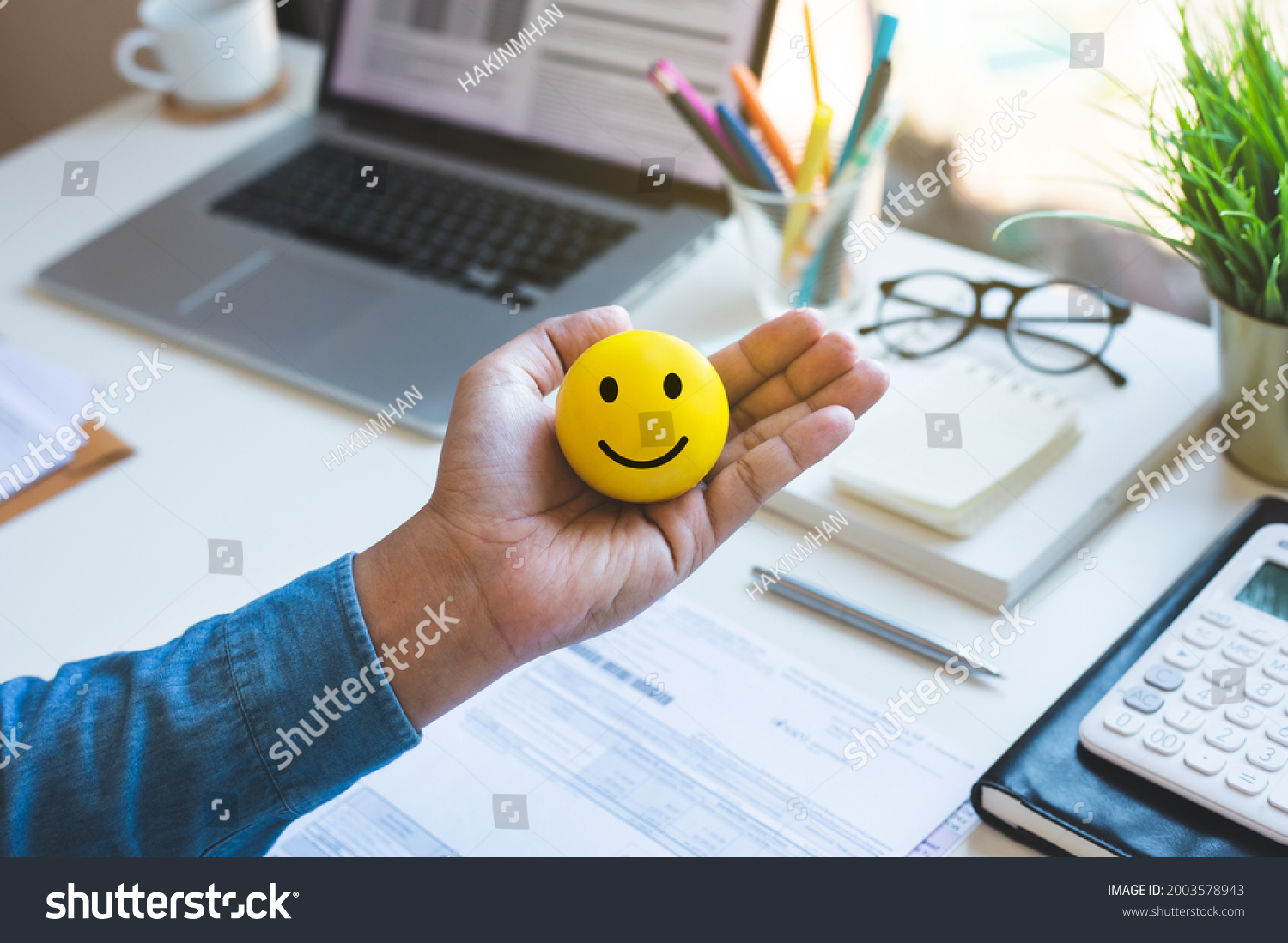 Emoticon ball on male hand on work table.happy life concepts.inspiration and motivation idea #2003578943