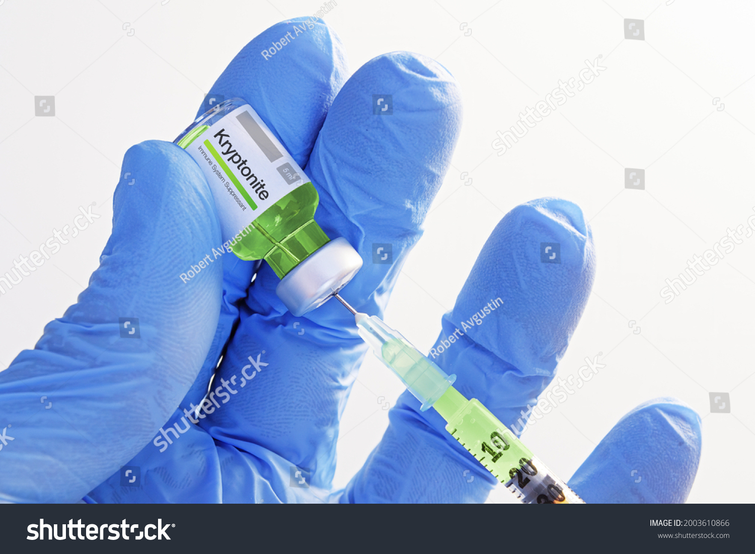 Close-up of hand in gloves holding a vial with kryptonite and extracting fluid to syringe for injection. Healthcare, medicine, pharmacy and vaccination concepts #2003610866