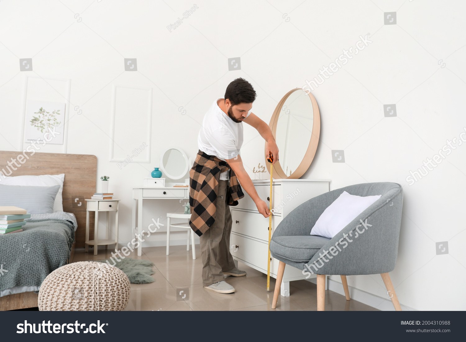 Male carpenter using tape measure in room #2004310988