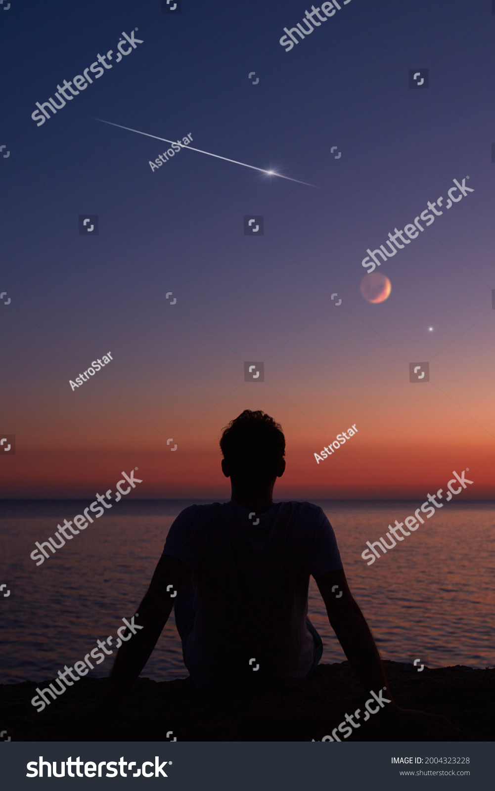 Silhouette of a man looking at the Moon and stars over sea ocean horizon. #2004323228