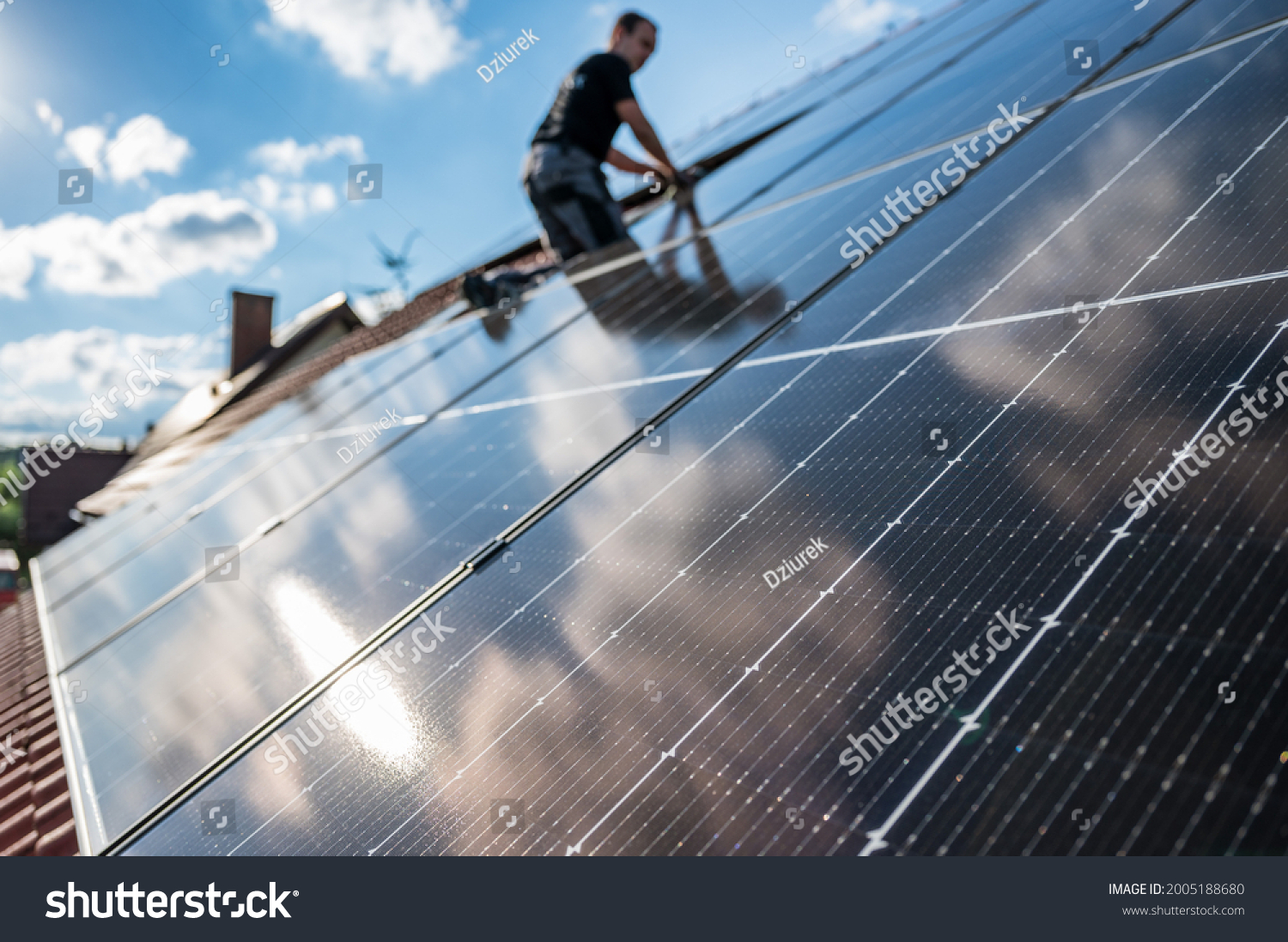 Photovoltaic panels on the roof and intaller in the background #2005188680
