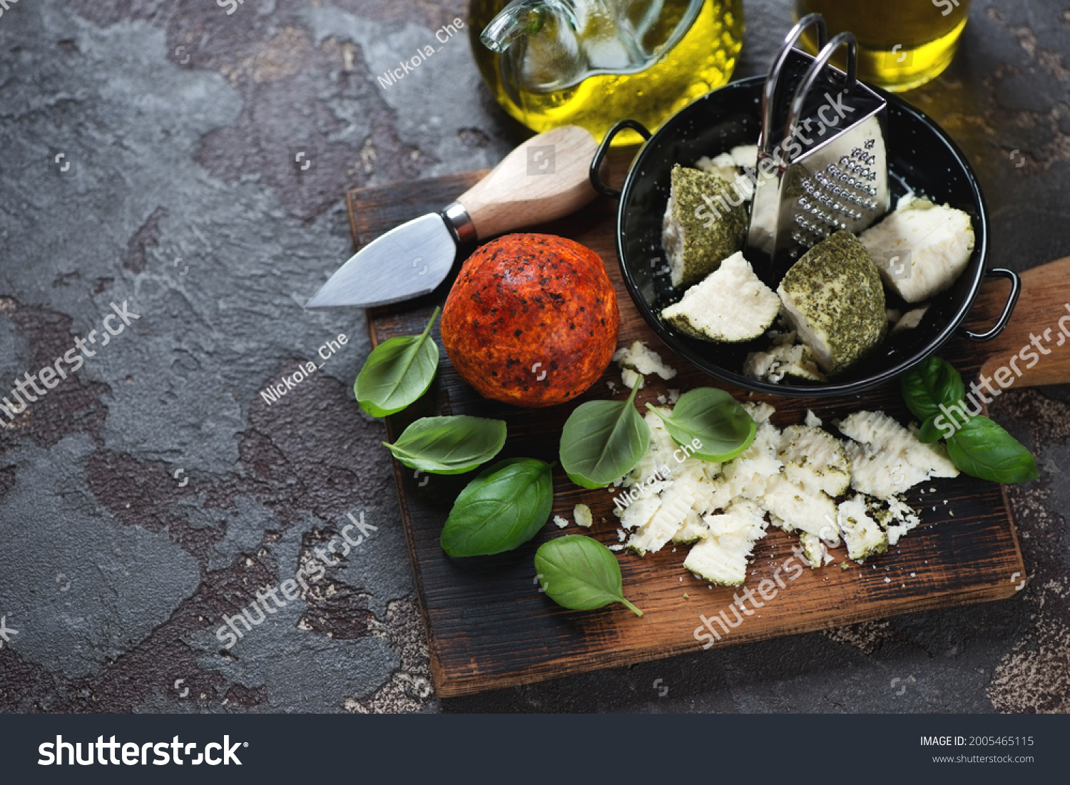 Swiss belper knolle cheese with green basil leaves and olive oil, horizontal shot on a brown stone background with space #2005465115