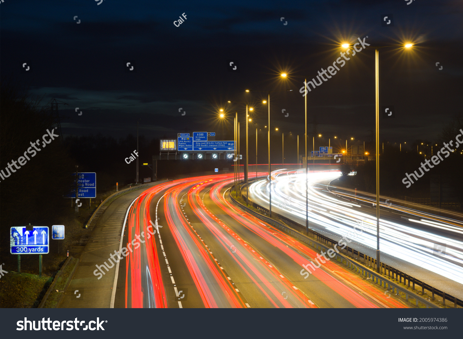 Smart motorway in England, UK with light trails signifying busy traffic at rush hour. The NSL symbols under the gantry sign signify an end to speed restrictions. #2005974386