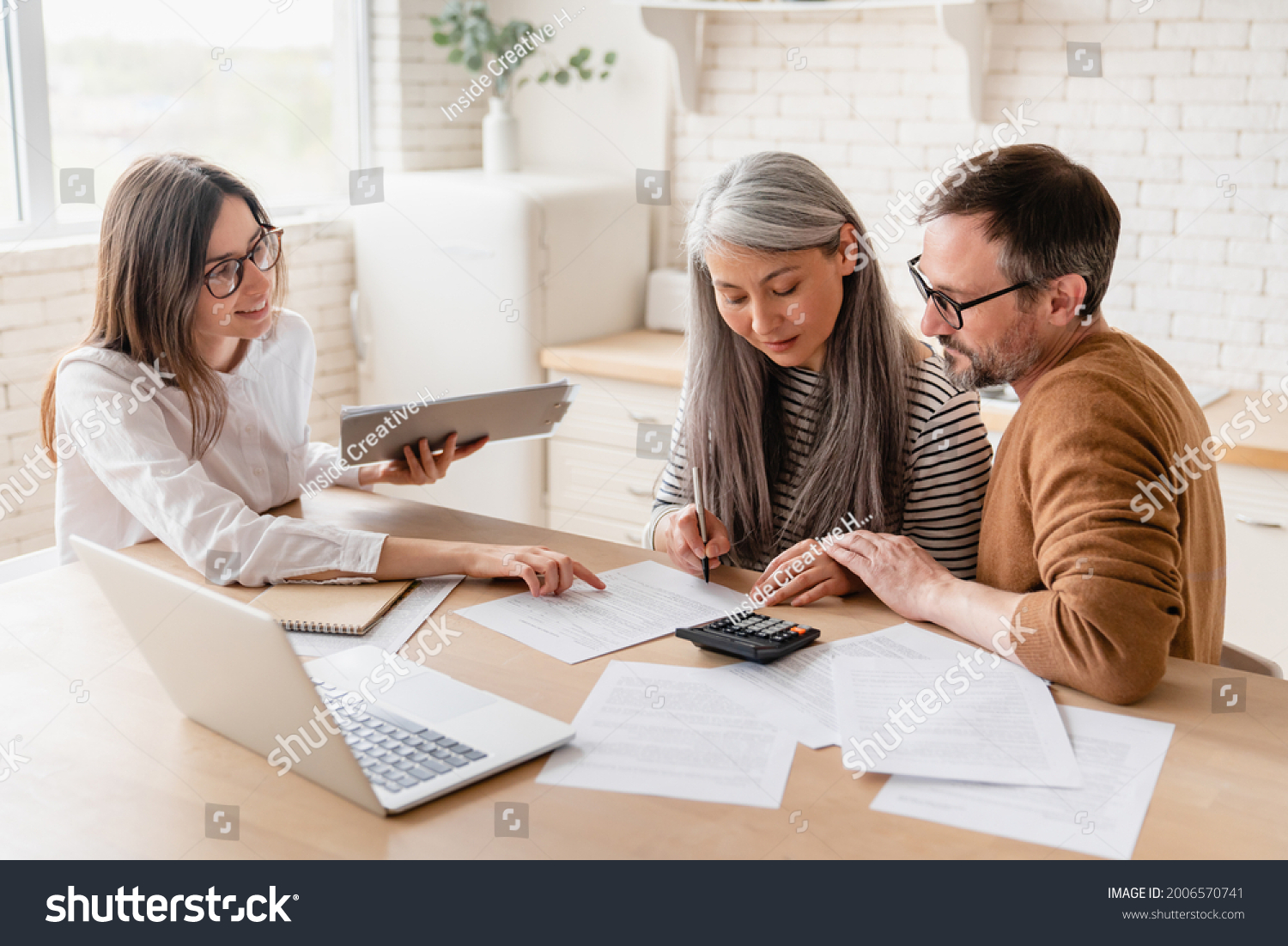 Insurance agent consulting mature family couple, discussing health insurance, signing contract deal of loan pension mortgage at home, calculating funds, investments, savings #2006570741