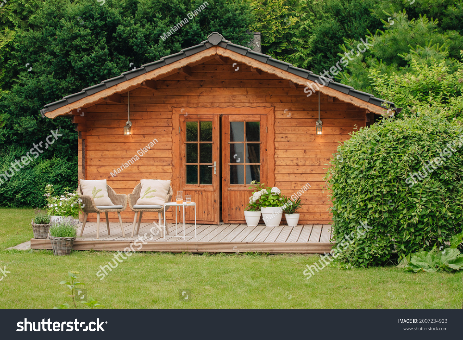 Modern garden chairs and flowers in front of a wooden hut. Garden joy in summer. Relax in the garden and enjoy the beautiful weather. Lavender and hydrangea in pot next to a garden shed  #2007234923