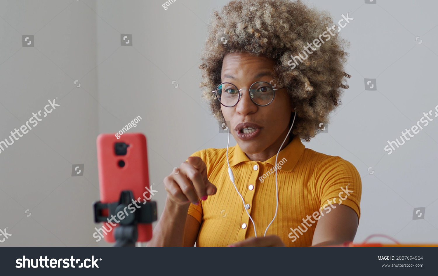 Black blogger woman recording video for social networks with a mobile phone while explaining. Content creator, influencer, streaming	 #2007694964
