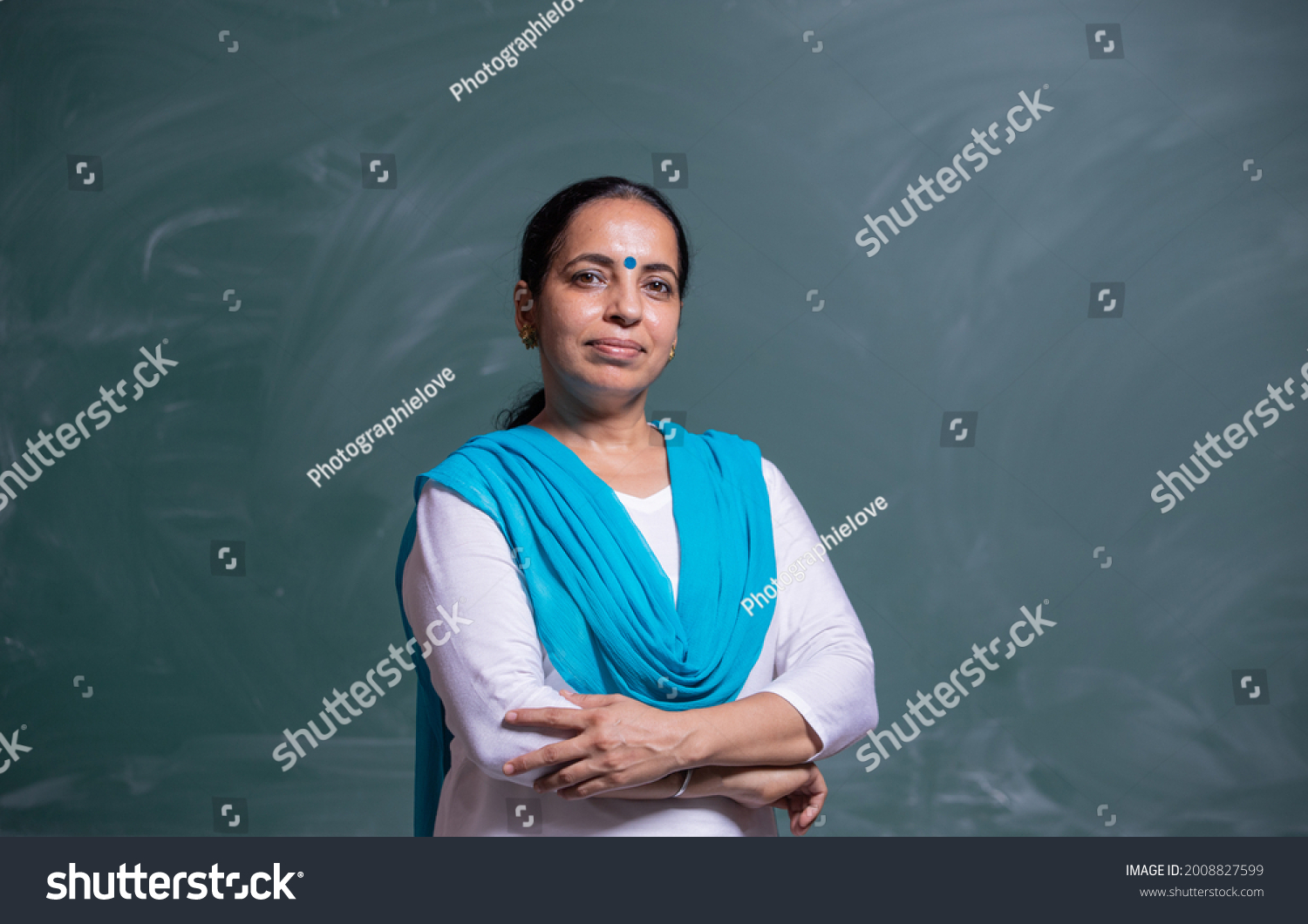 portrait of confident Indian teacher standing in front of the black board in class room #2008827599