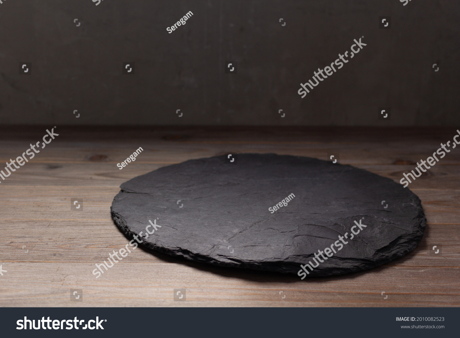 Slate pizza cutting board for homemade bread cooking or baking on table. Empty pizza board at wooden tabletop background. Bakery concept in kitchen #2010082523