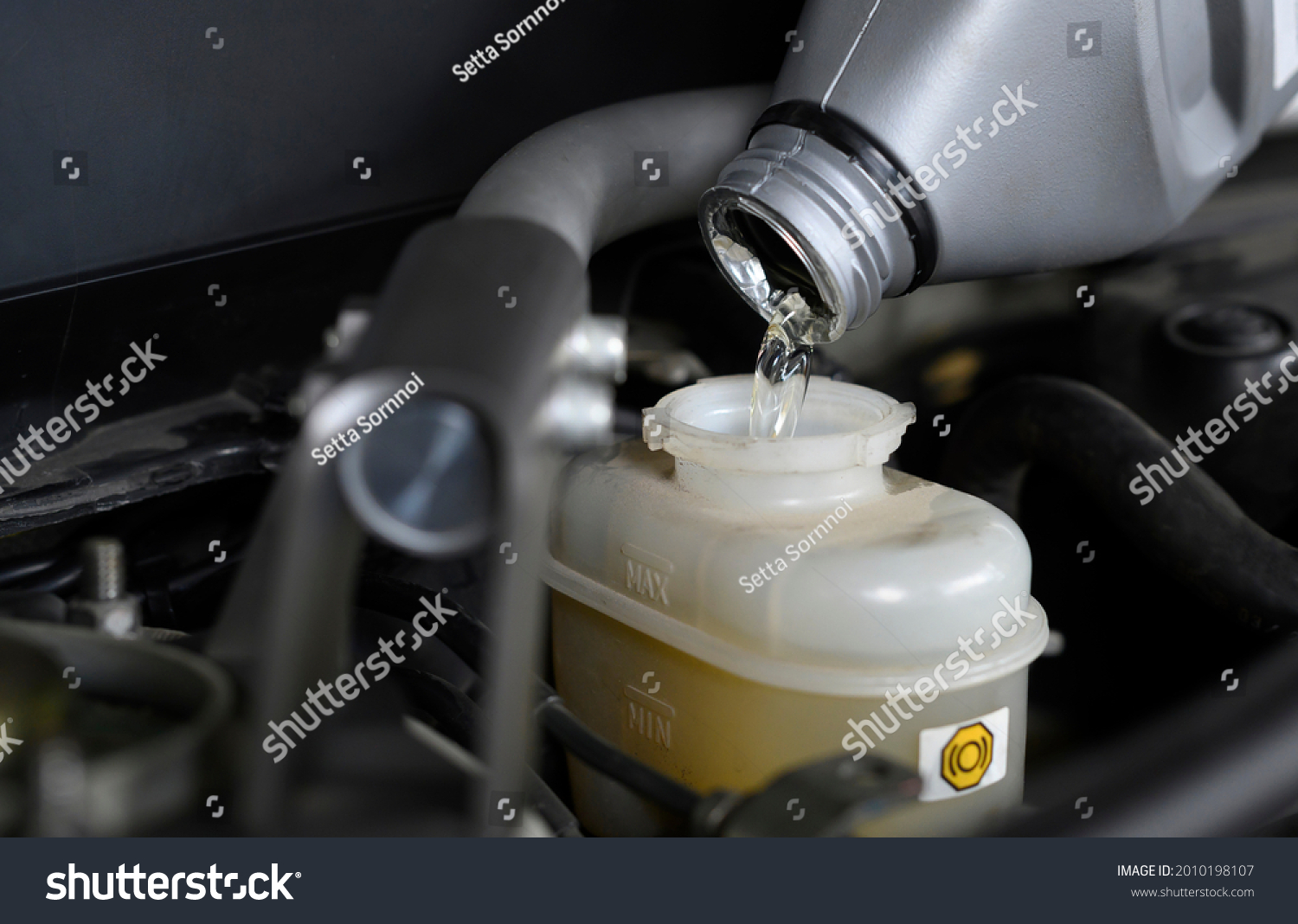 Auto mechanic filling brake fluid in brake fluid reservoir. #2010198107