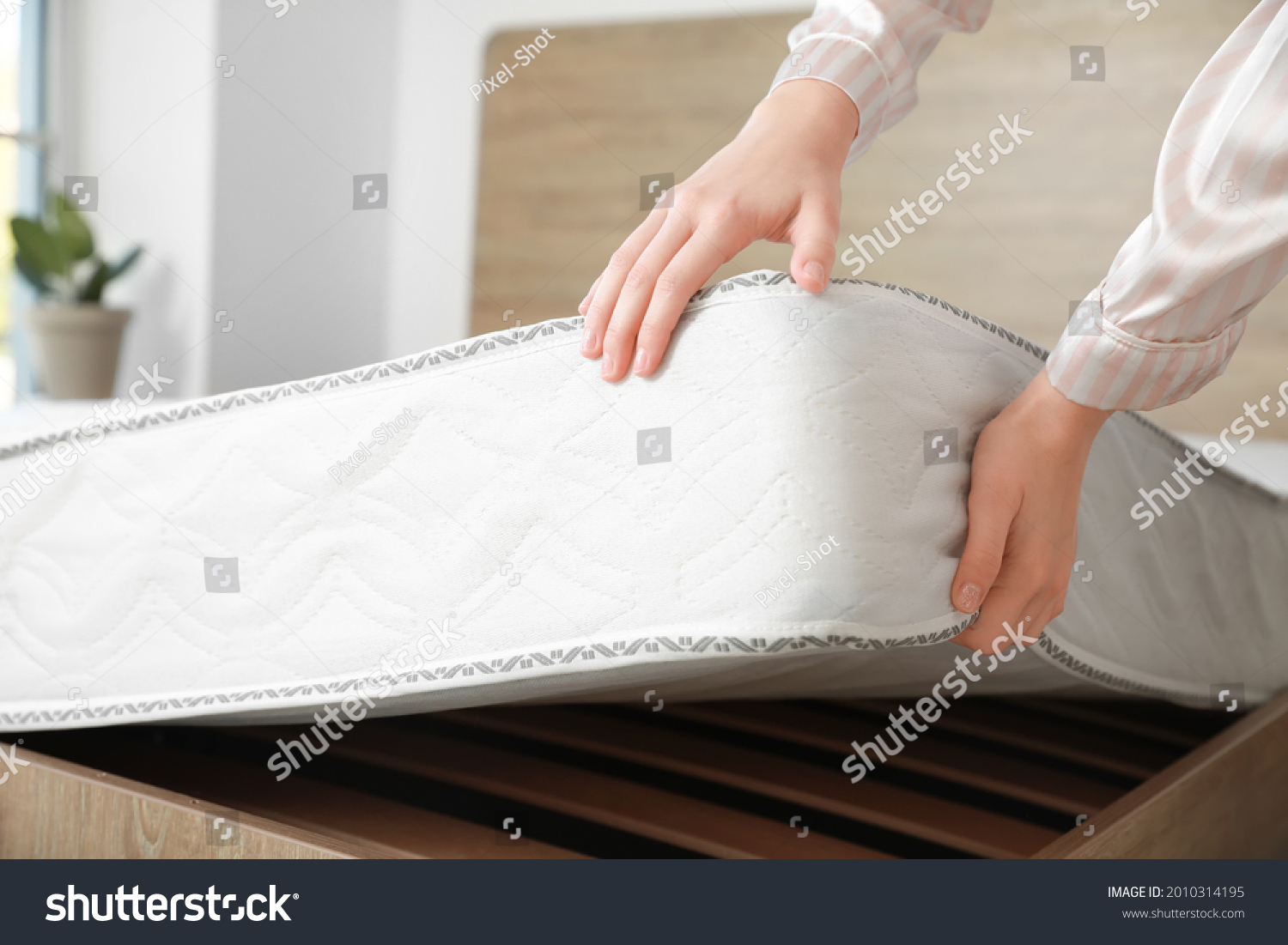 Woman putting soft orthopedic mattress on bed #2010314195