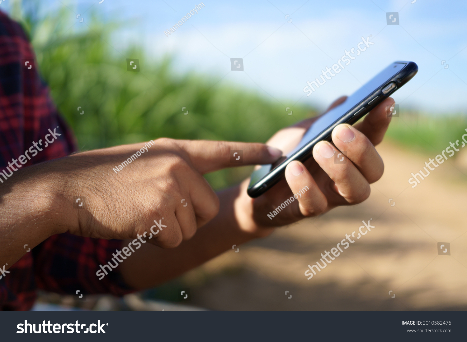 The farmer holds a smartphone and touches the screen to connect the intelligent management system within the farm. smart farmers research and market information online. #2010582476