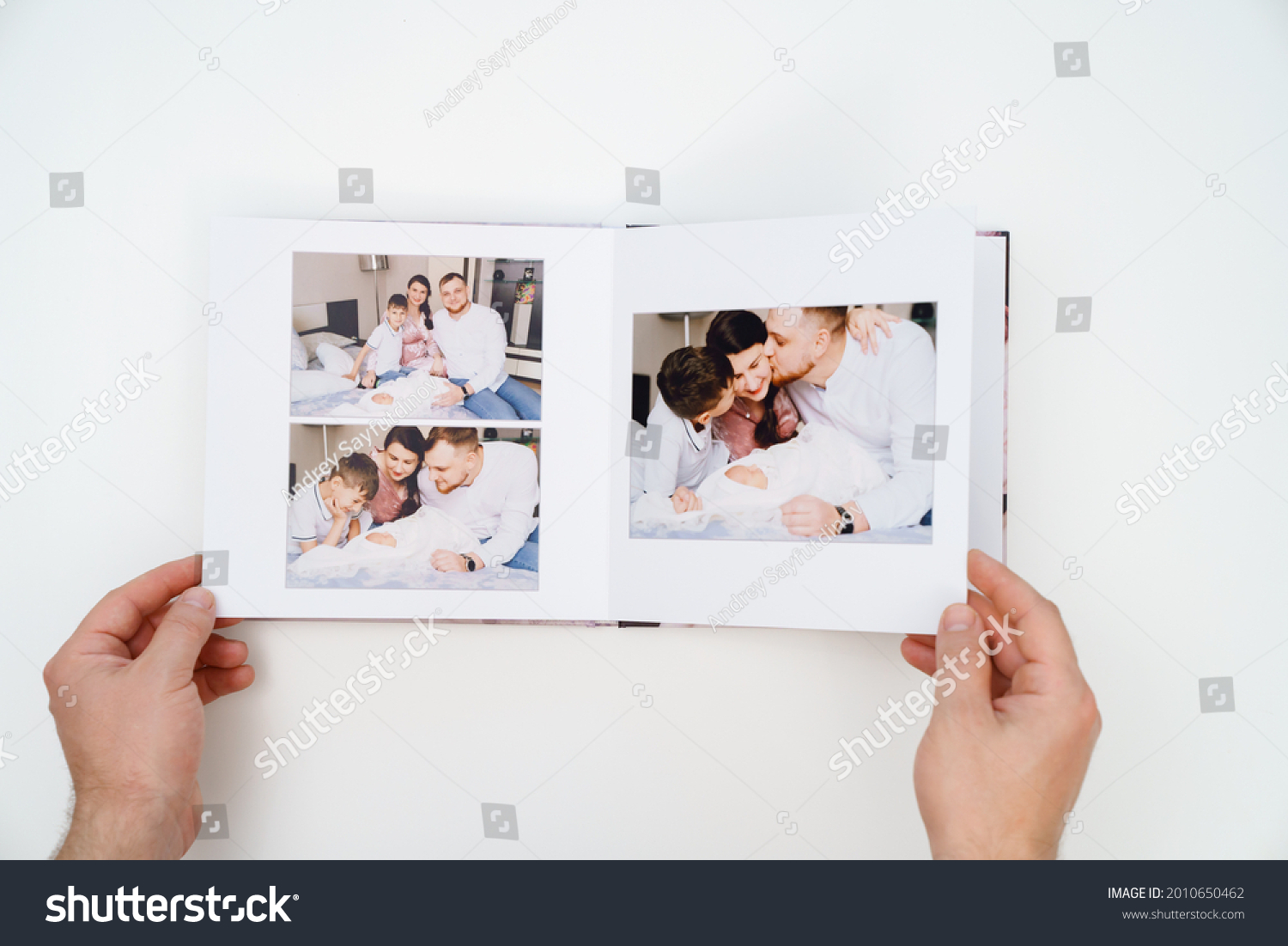 on a white background, hands flip through a photobook from a home family photo shoot with a newborn child. traditions to make a photo album and print photos from important moments of life. #2010650462
