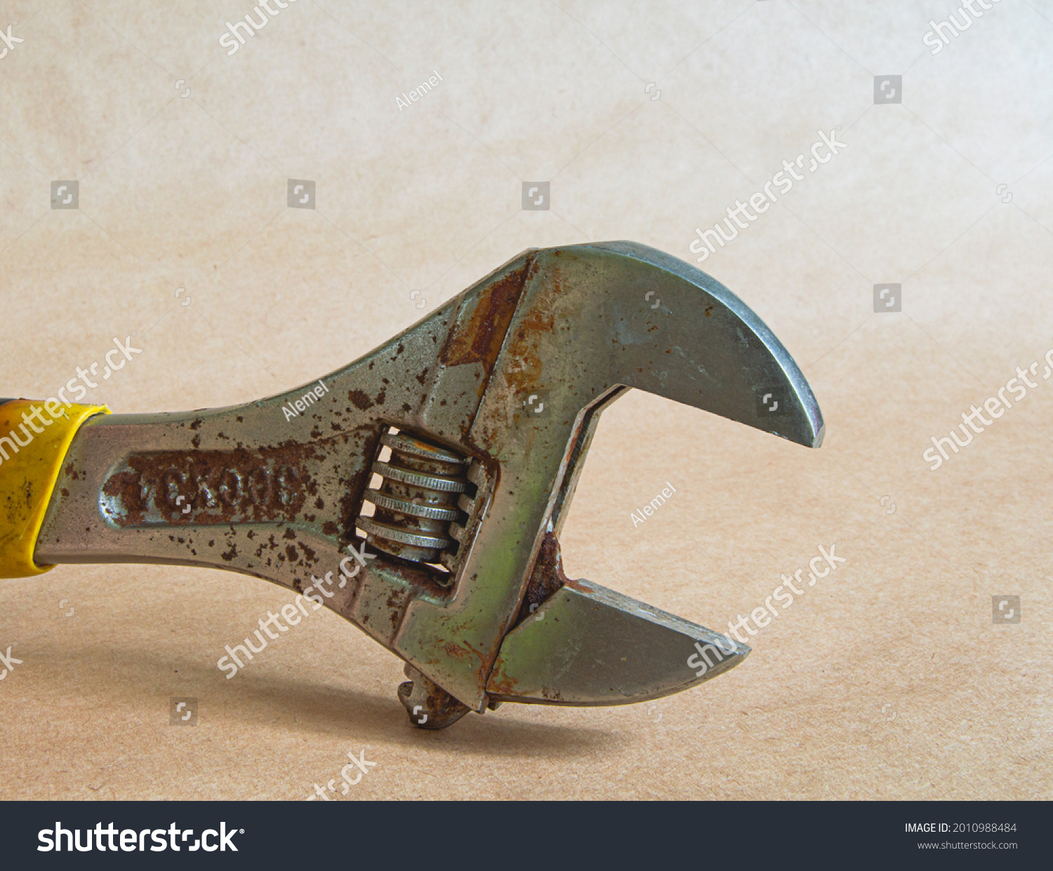 Rusty adjustable wrench isolated on vintage background. Plumbing tool. Joiner's tool. Macro. #2010988484