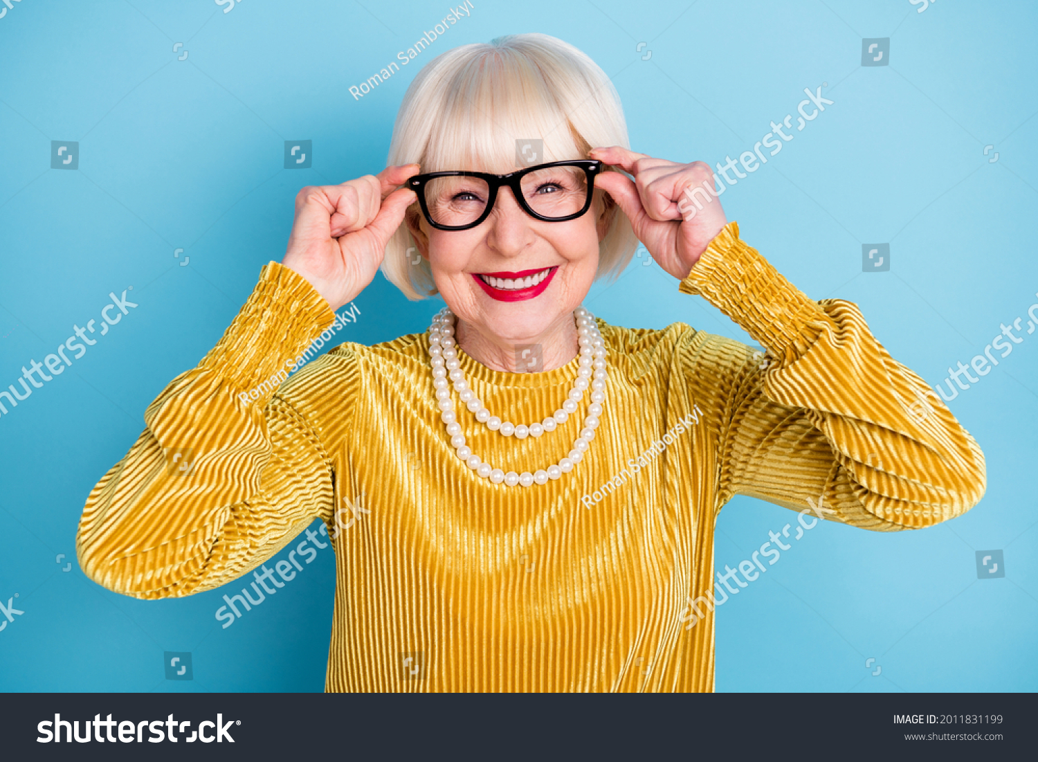 Photo of cheerful short hairdo senior lady hands eyewear wear blouse necklace isolated on blue color background #2011831199
