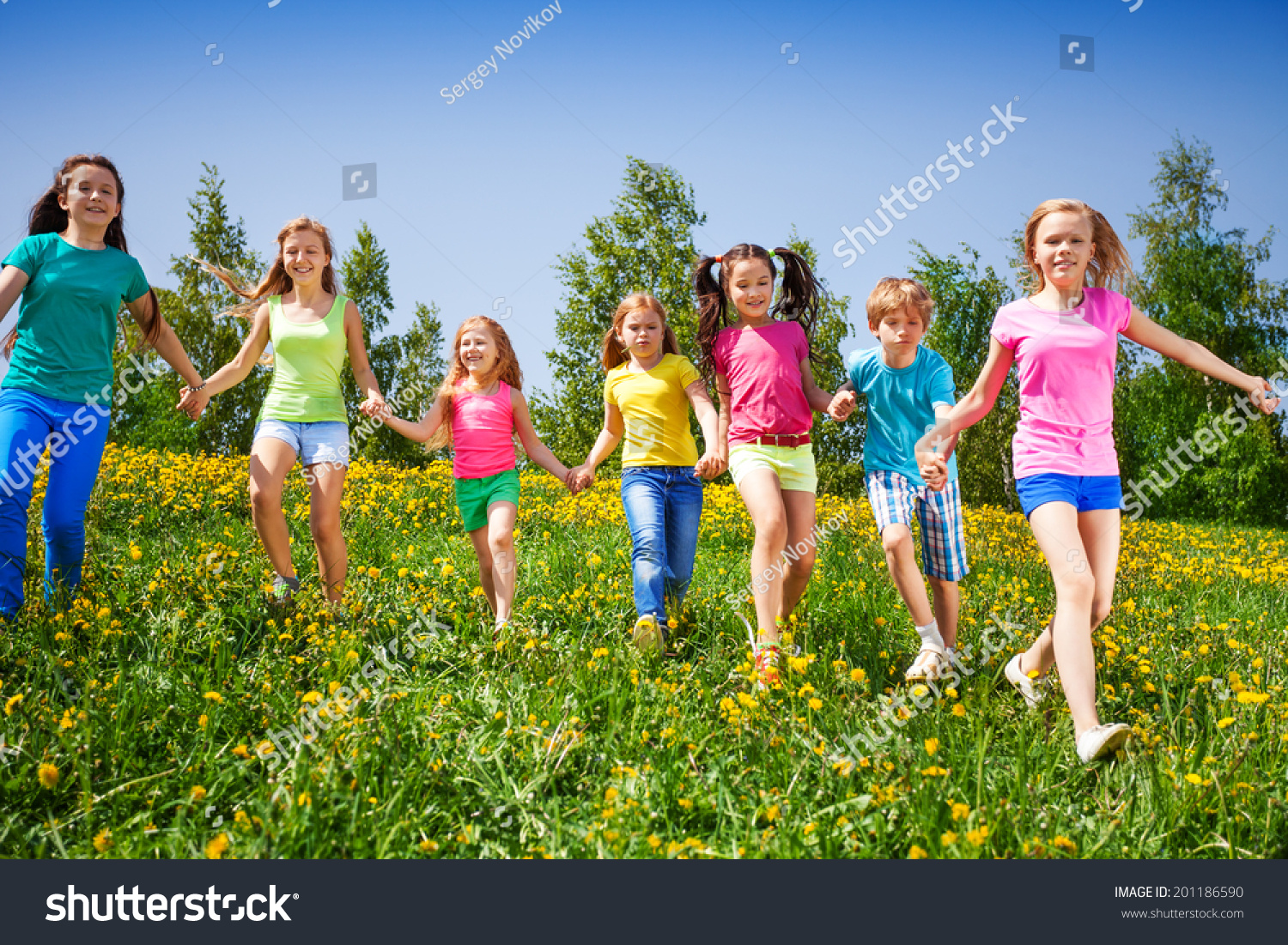 Happy children run and hold hands in green field #201186590