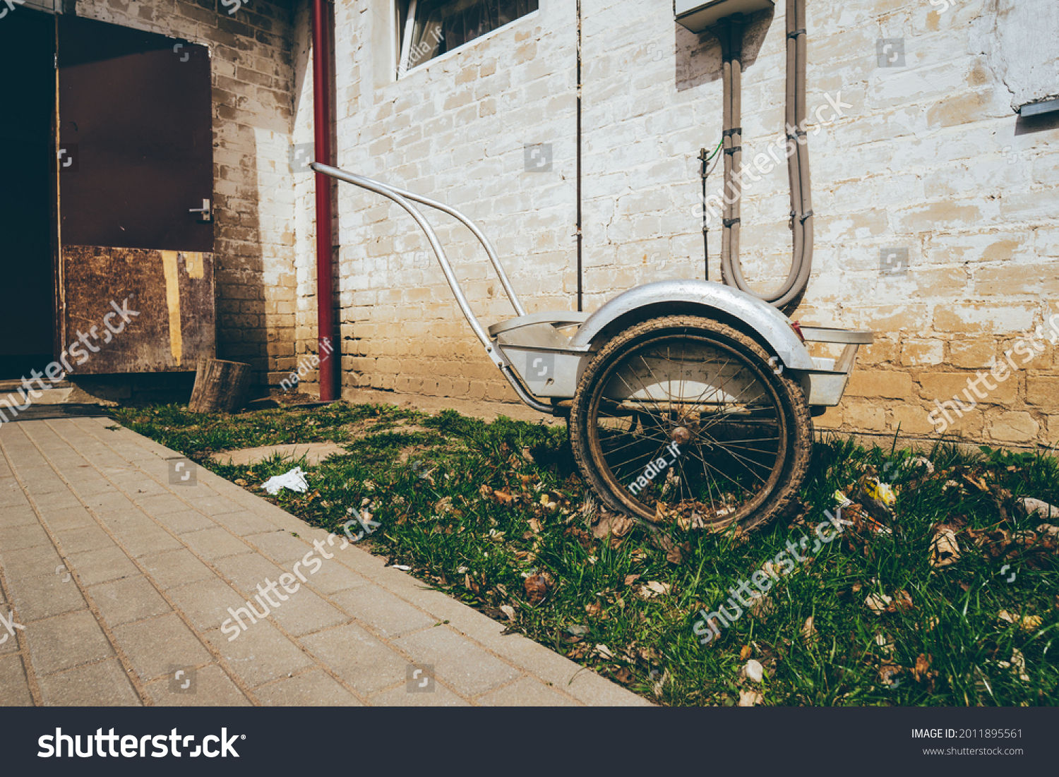 Wheelbarrow on a grass field with an interesting background of an old house . High quality photo #2011895561