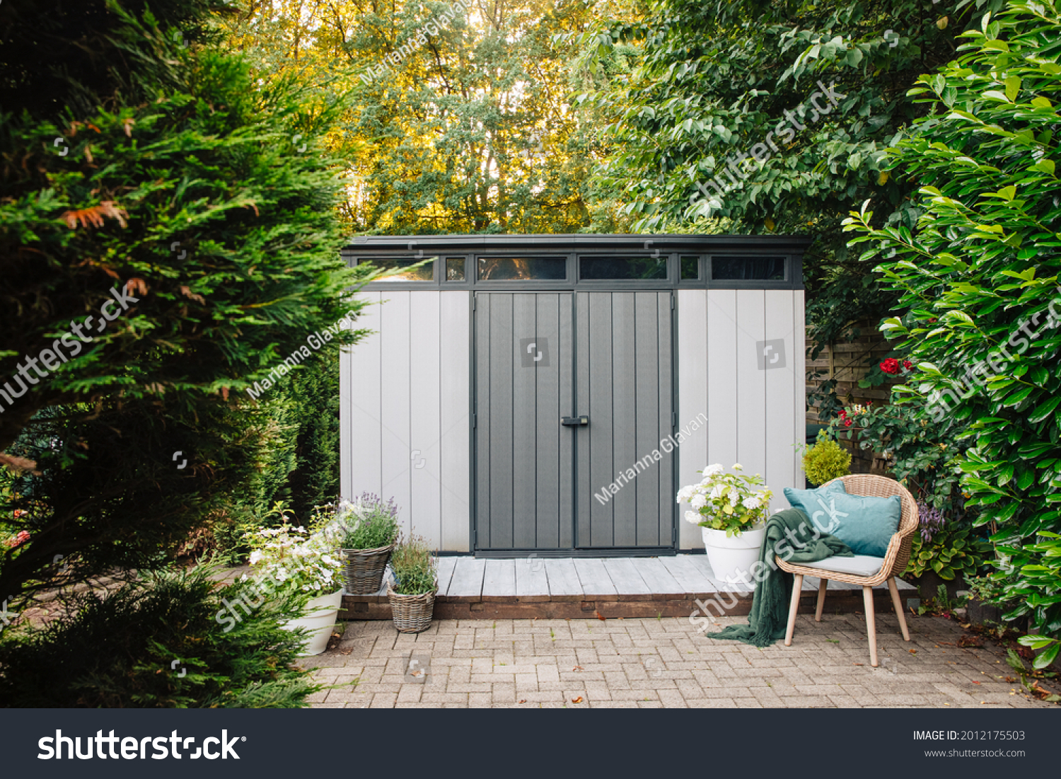 Gray garden shed in summer. Lots of pots of flowers next to a plastic garden shed. Relax in the garden. Big garden in Germany  #2012175503