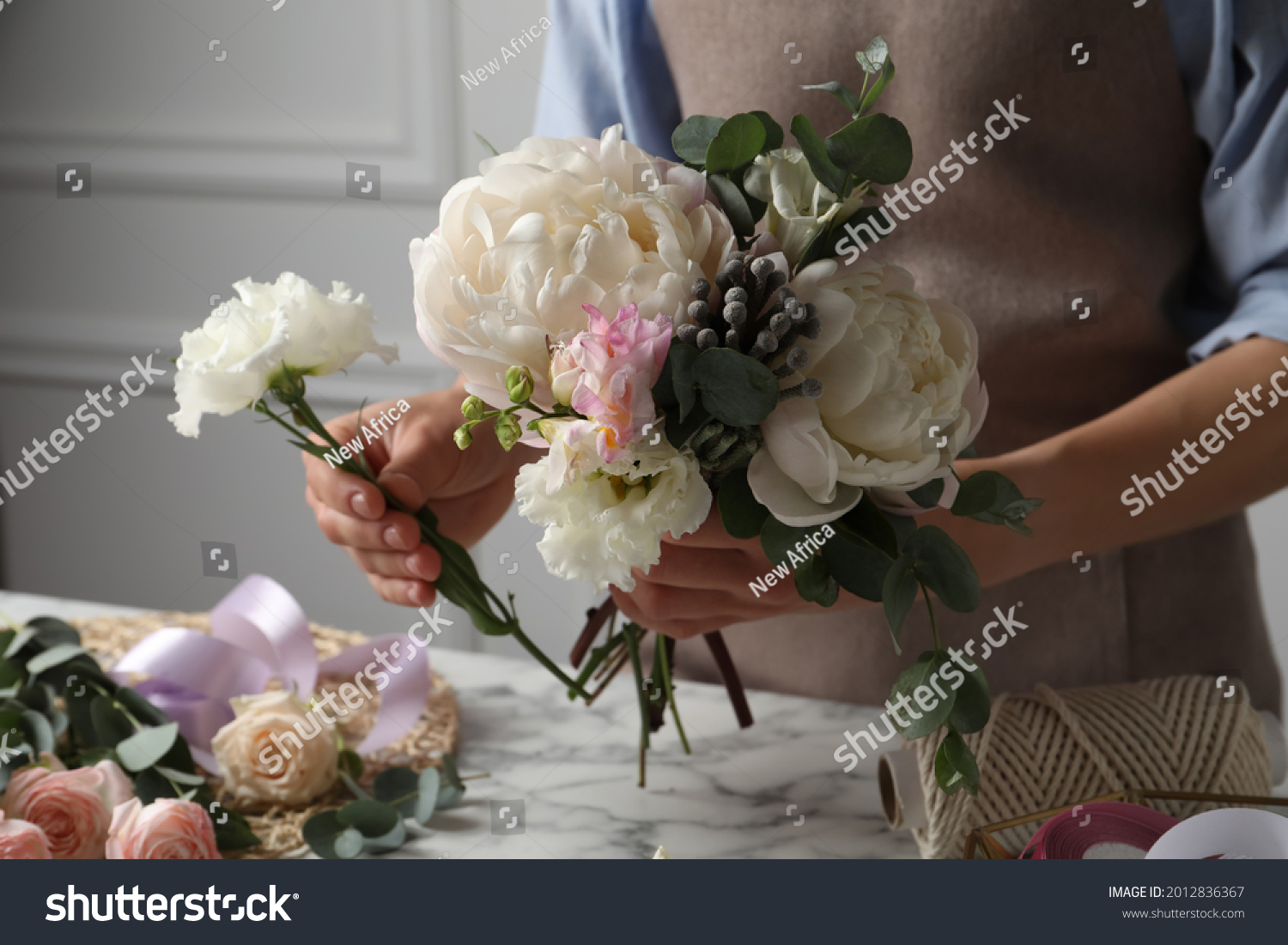 Florist creating beautiful bouquet at white marble table, closeup #2012836367