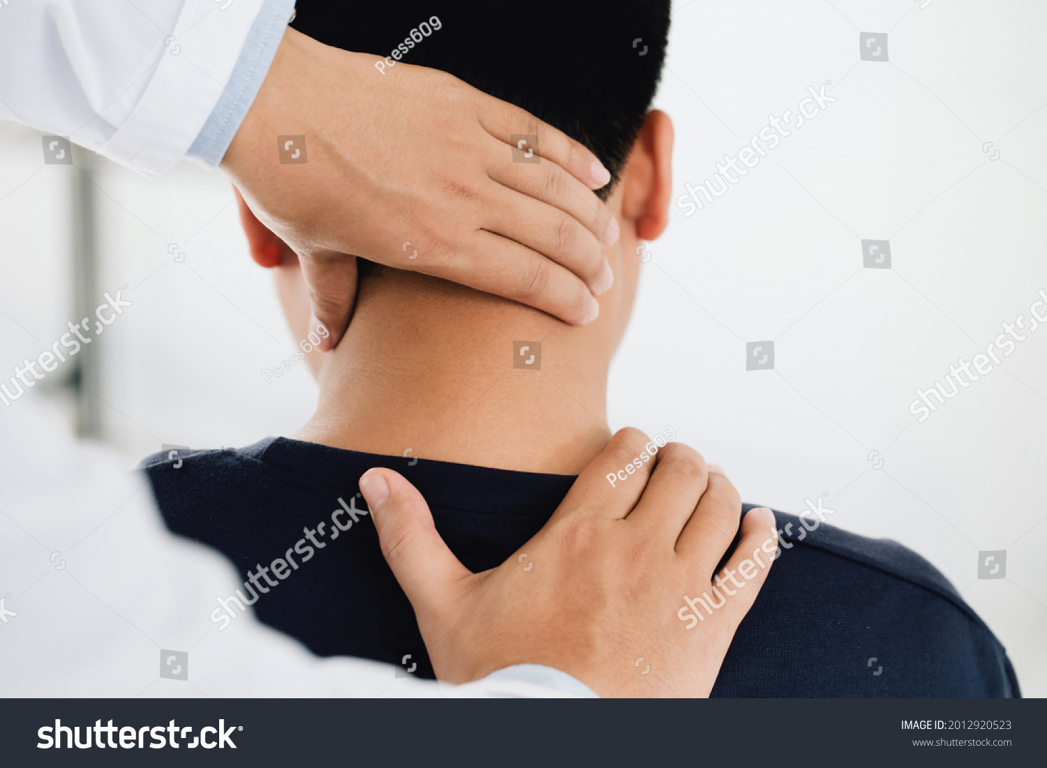 physiotherapist massage therapist holding male client's head and massaging tight neck muscles the result of prolonged use of mobile phones.Office Syndrome #2012920523