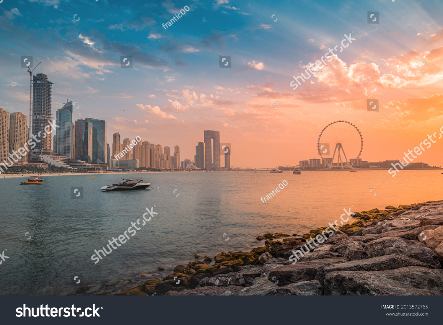 A delightful and colorful sunset over Blue waters Island with the famous Dubai Eye Ferris wheel. Panoramic view of the city in UAE #2013572765