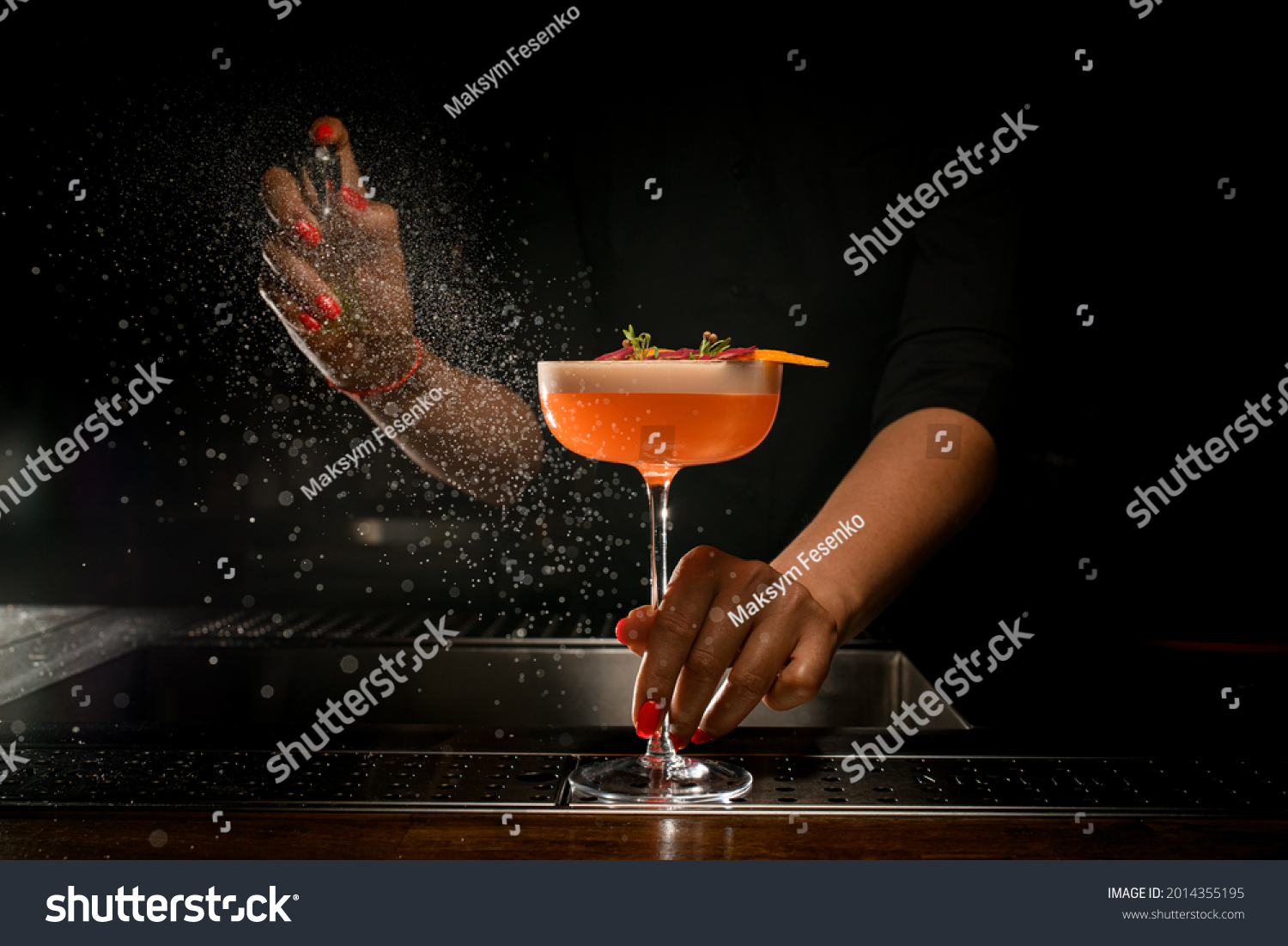 direct view of glass with bright delicious frothy cocktail that woman bartender holds with her hand and sprinkles on it. A lot of drops around #2014355195