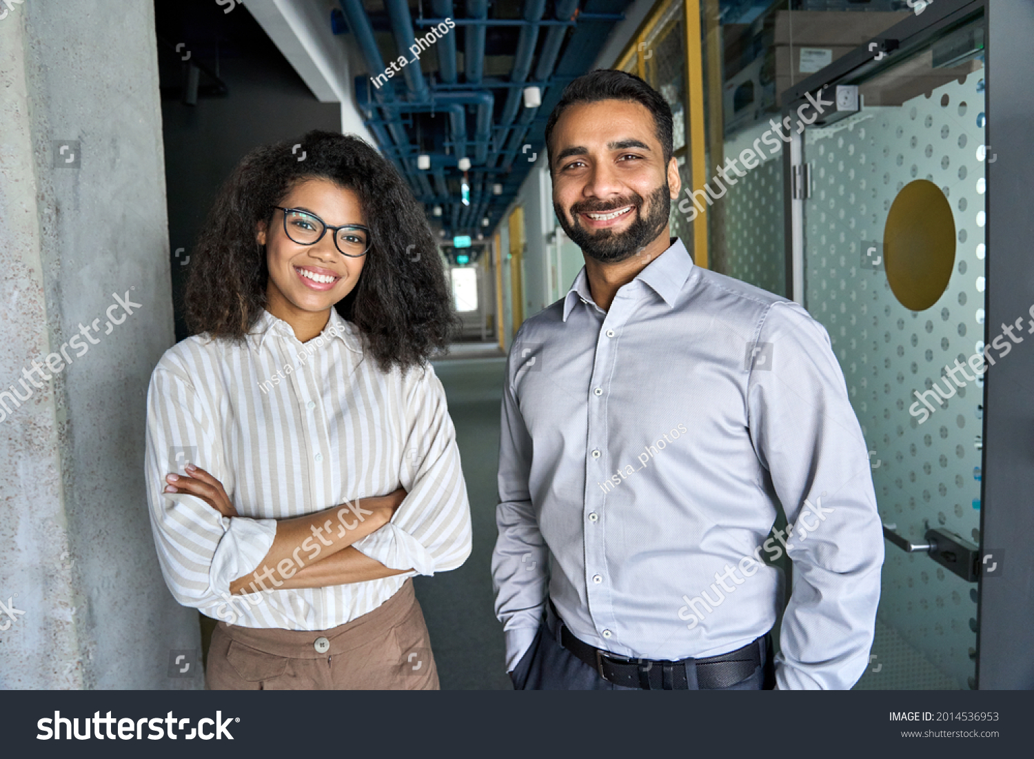 Two happy diverse professional executive business team people African American woman and Indian man looking at camera standing in office lobby hall. Multicultural company managers team portrait. #2014536953