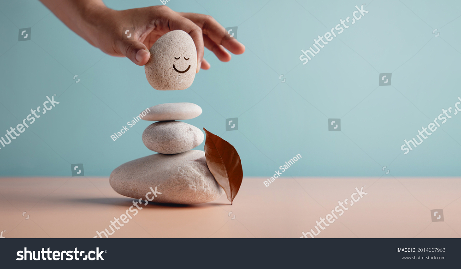 Enjoying Life Concept. Harmony and Positive Mind. Hand Setting Natural Pebble Stone with Smiling Face Cartoon to Balance. Balancing Body, Mind, Soul and Spirit. Mental Health Practice #2014667963