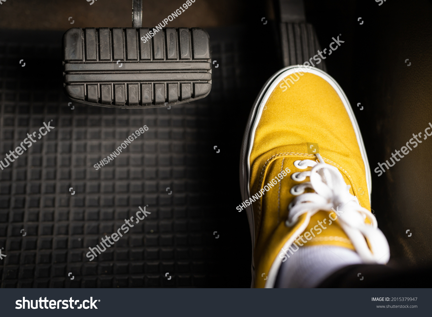 A man in yellow sneakers is stepping on the accelerator of a car. #2015379947