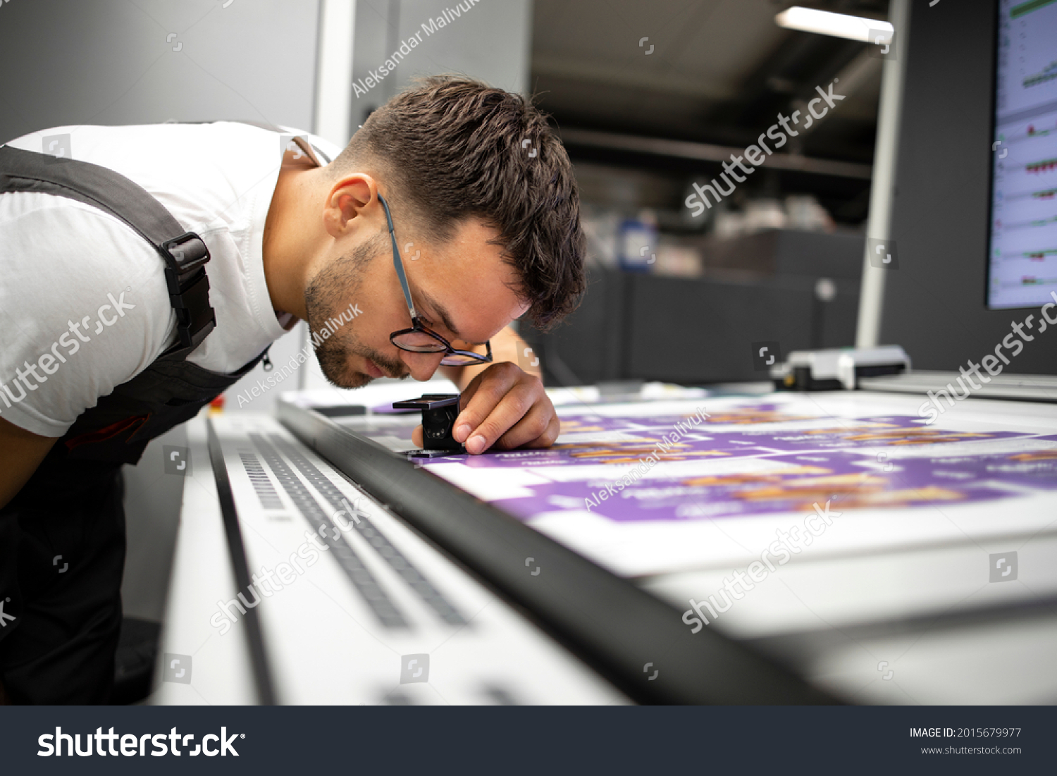 Worker checking print quality of graphics in modern printing house. #2015679977