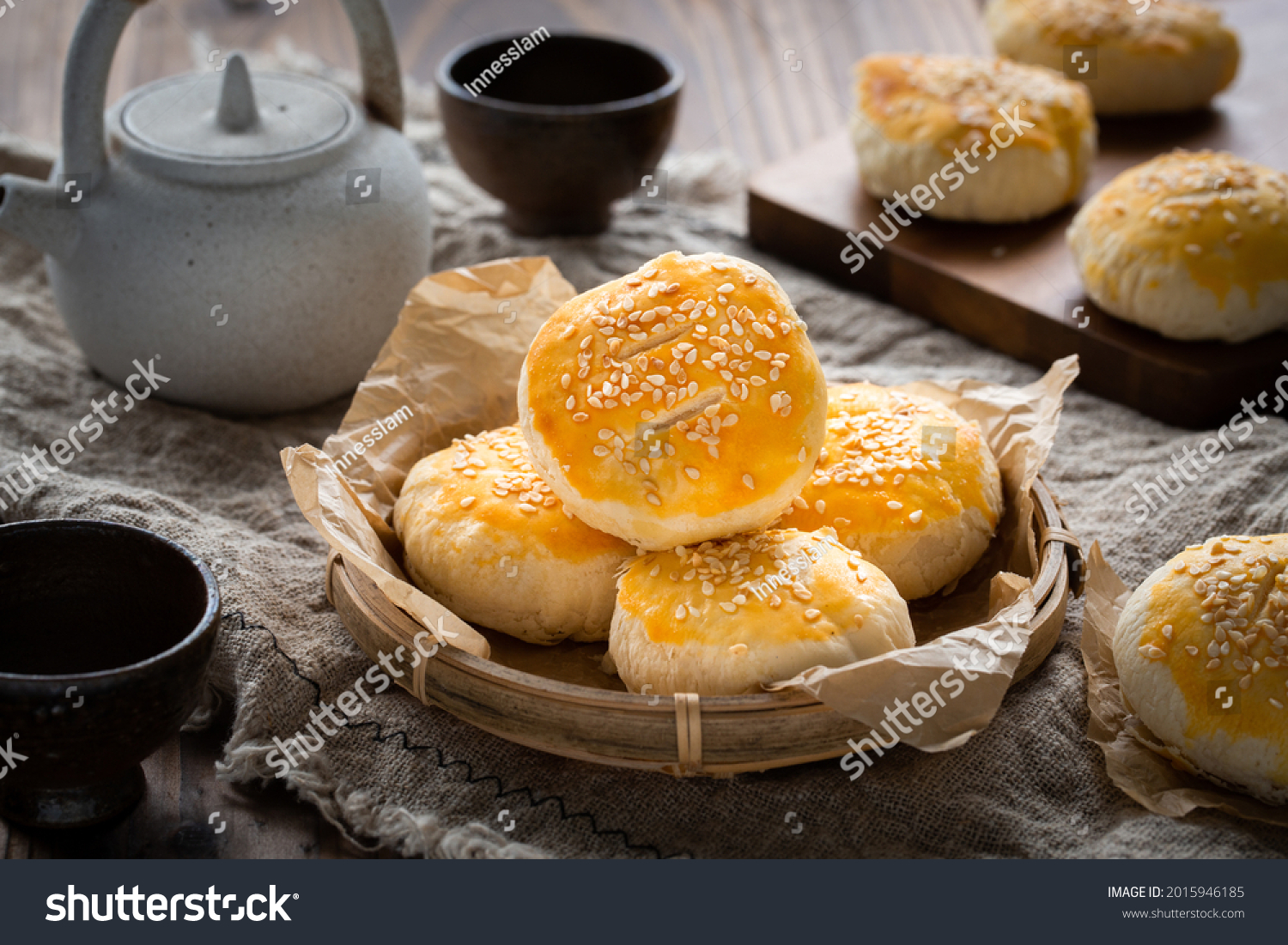 Traditional Chinese Cantonese pastry Sweetheart Cake or Lo Po Beng placed on a bamboo plate on a wooden table. there are also a tea pot and two tea cups as well as some more cakes. #2015946185