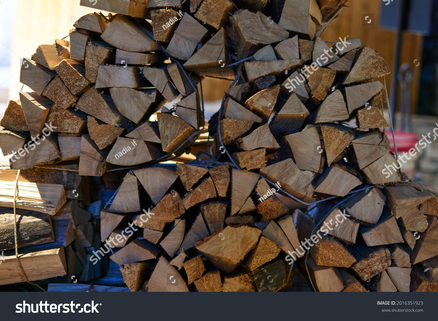 A beautiful closeup view of cut and split firewood stacked outdoor up against a shed under roof . High quality photo #2016351923