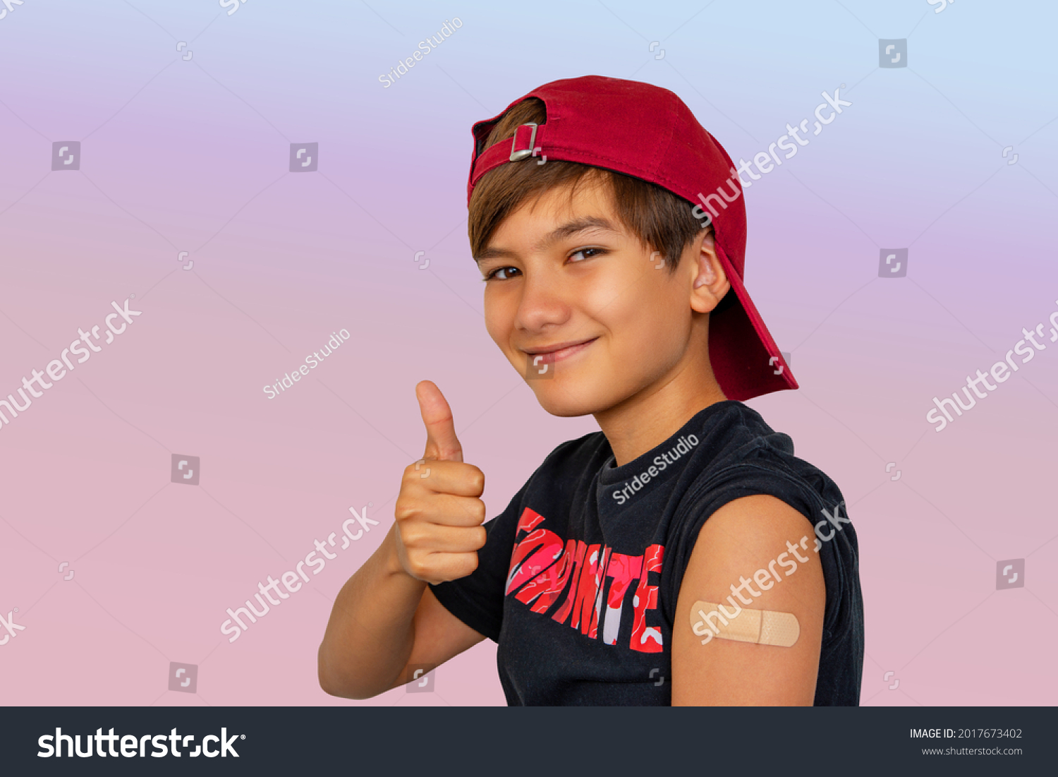 Portrait Of boy11-12 years old boy got HPV vaccine to prevents infection from the strains of HPV cancer. BoSy with Vaccinated Arm With Sticking Patch On the Shoulder After Getting Shot And Thumb Up.  #2017673402