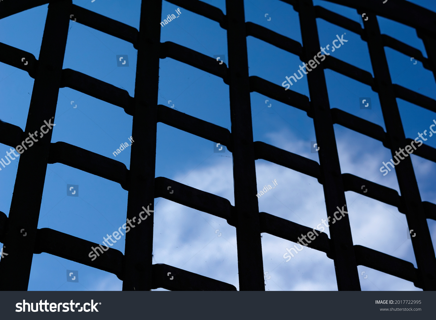 Selective focus, texture of a metal old lattice fence against the blue sky, fence lattice, lattice background, cell. High quality photo #2017722995
