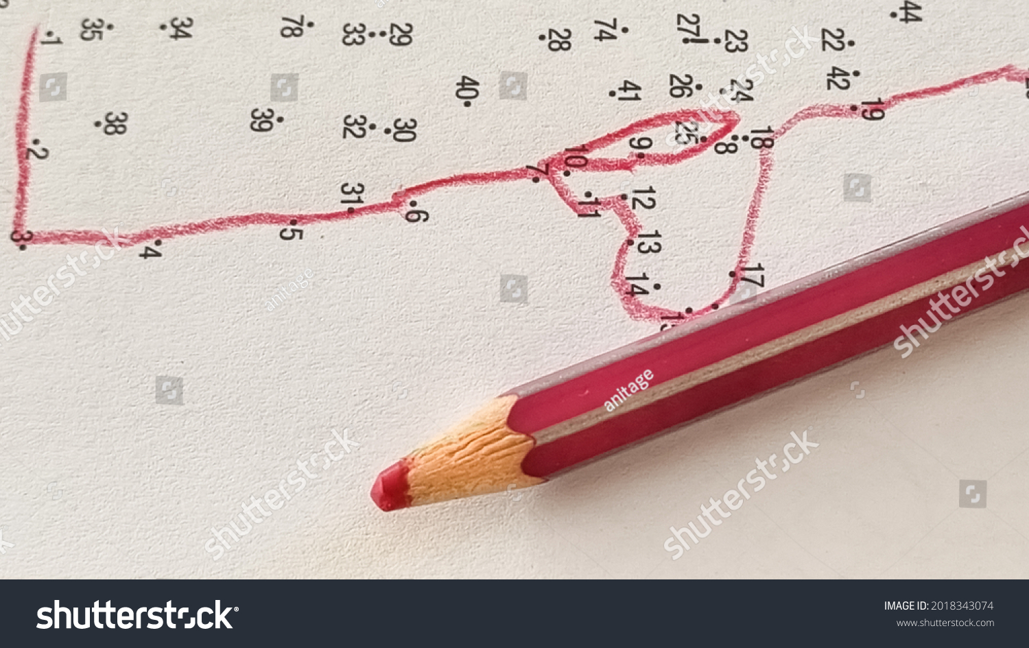  Connecting dots with numbers with a line with a red pencil. Drawing game. No straight lines. Step by step, small steps, patience concept. Close up. #2018343074
