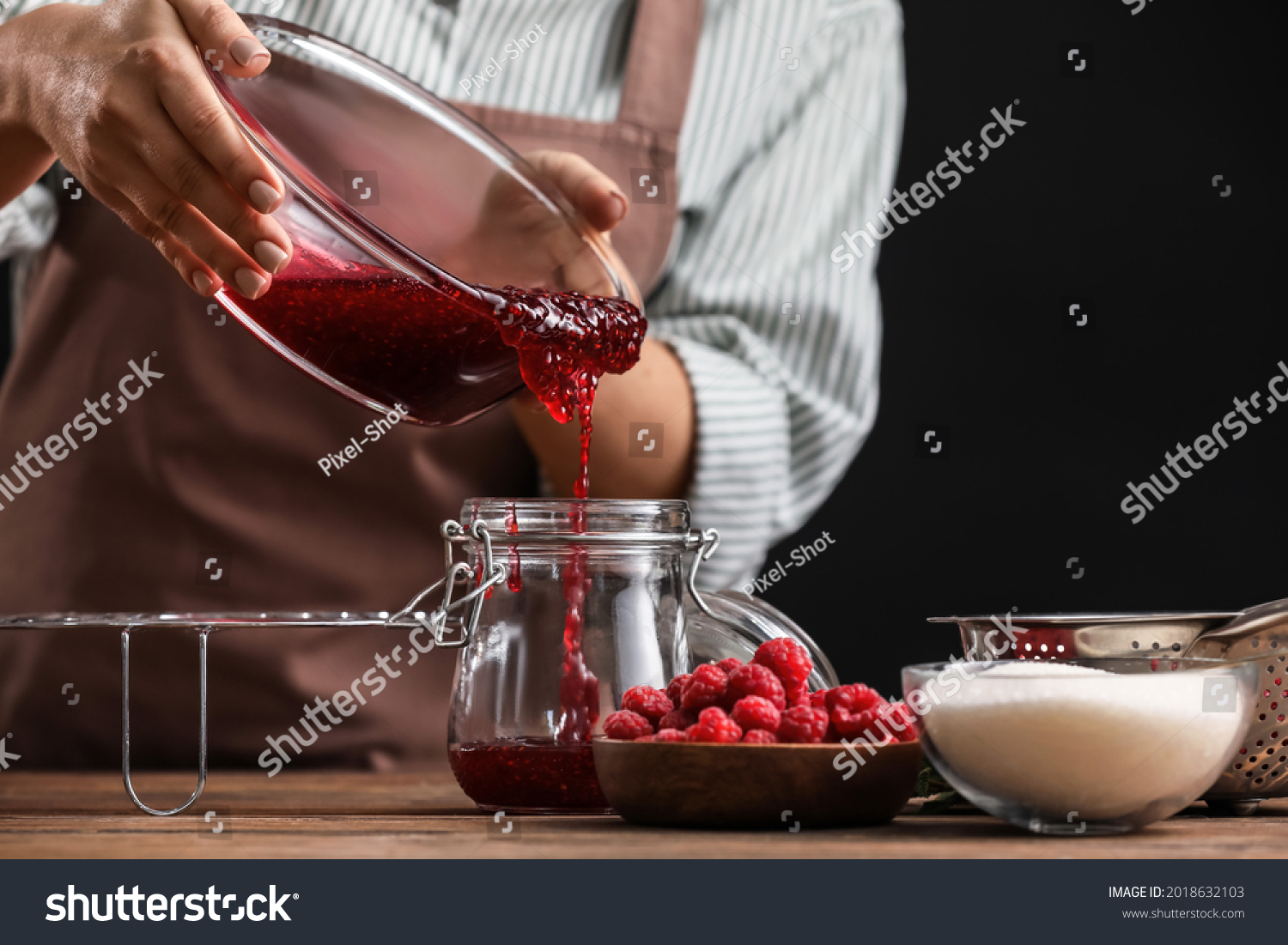 Woman cooking sweet raspberry jam in kitchen #2018632103