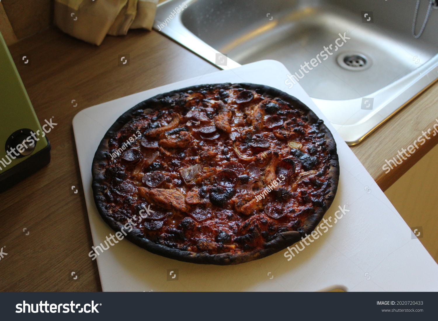 Burnt pizza on a chopping board #2020720433