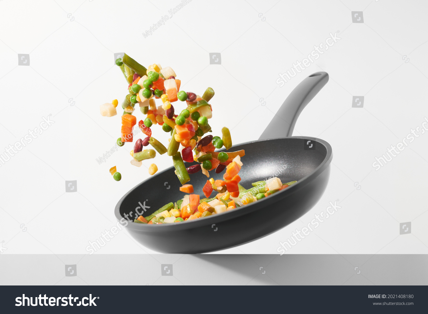Fresh vegetables fly in a pan on a white background. Cooking with various chopped vegetables in a pan. The concept of healthy eating and diet. 
 #2021408180