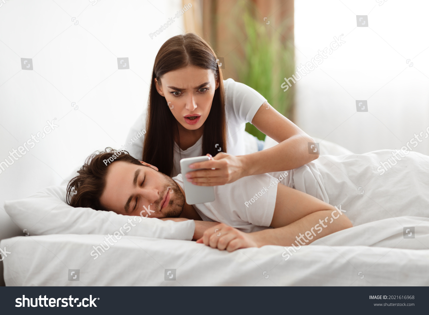 Infidelity. Shocked Wife Reading Message From Lover On Phone While Cheating Husband Sleeping In Bedroom At Home. Jealous Woman Checking Boyfriend's Cellphone Chats. Affair, Relationship Issues #2021616968