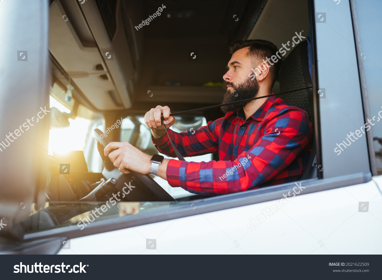 Truck driver fastens seatbelt  and preparing for the next destination. #2021622509