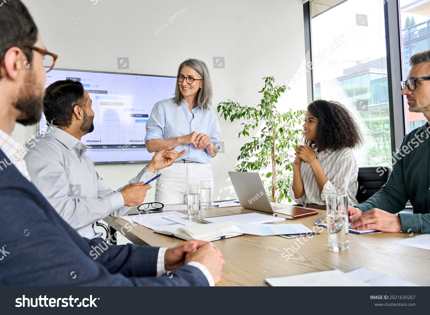 International executive team people having board meeting discussing project results. Diverse employees group working with senior leader brainstorming in office meeting room at presentation training. #2021639267