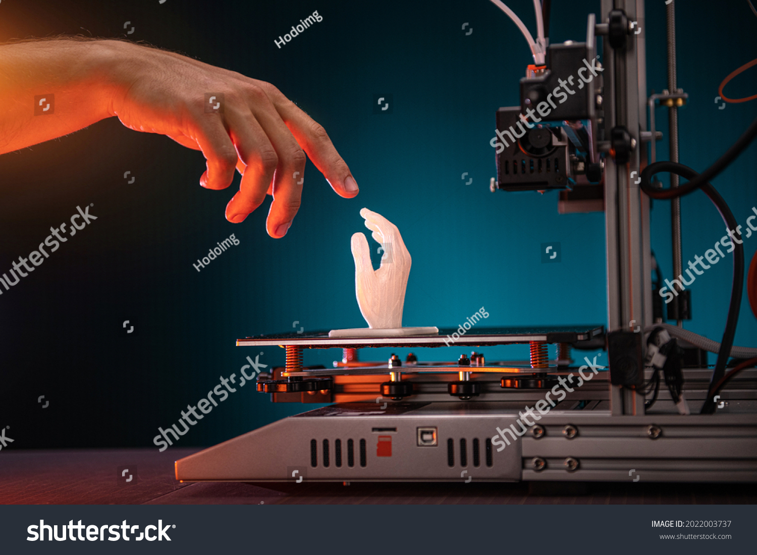 3D printing in progress. 3d printer printed a hand. A man touches the product printed on a 3d printer. God's touch, biblical motives. High quality photo #2022003737